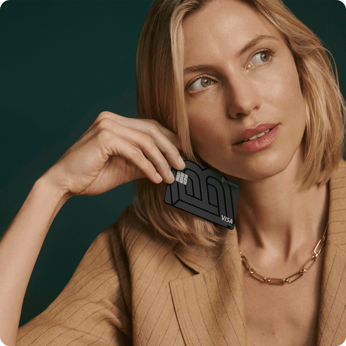 Woman in a beige blazer holds a black Visa card to her face, looking thoughtfully to the side against a dark green background.