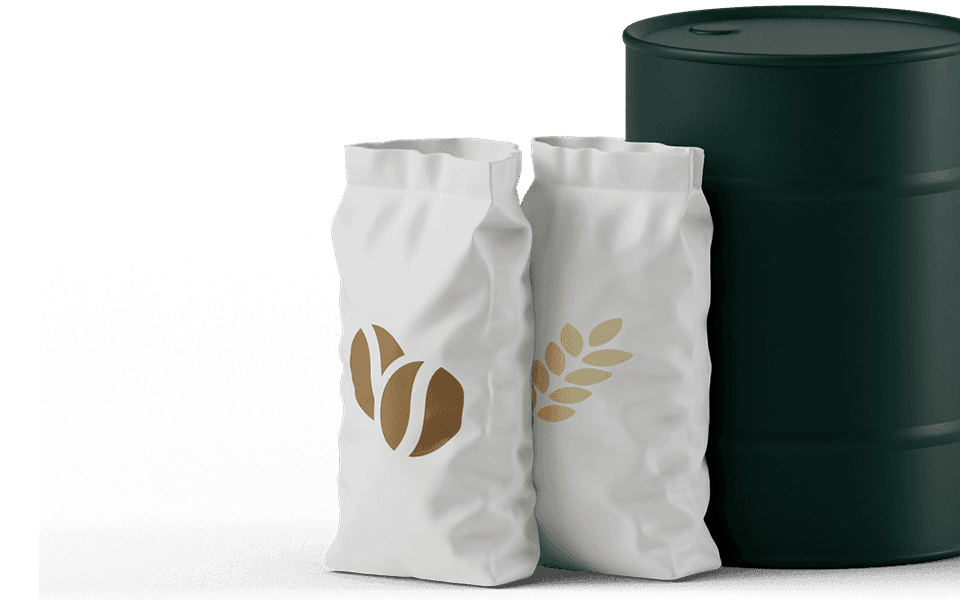 Two white bags with gold leaf and coffee bean designs stand next to a dark green barrel.